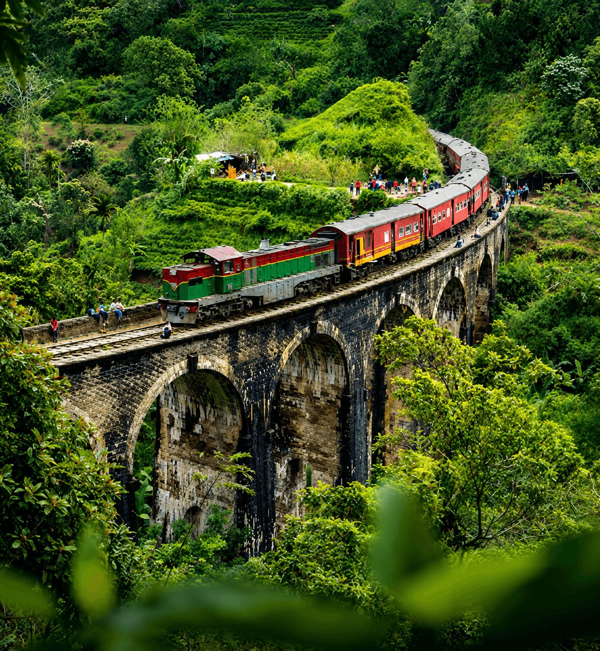 Train crossing a stone bridge through lush highlands