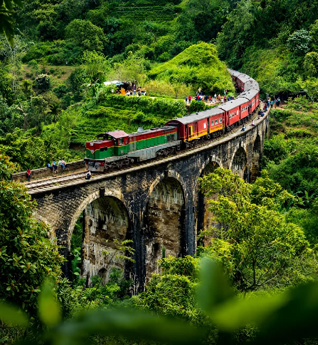 Train crossing a stone bridge through lush highlands